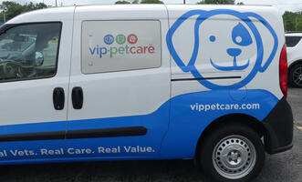 Side of pet care van with large icon of dog face in blue