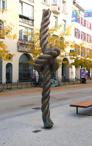 Sculpture of a piece of rope standing vertically. There is a knot in the rope. Sculpture is 3.5 meters tall.