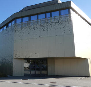 Large modernist building with array of irregularly spaced dots on the walls.