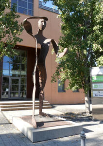 Large abstract rust-colored statue of a person