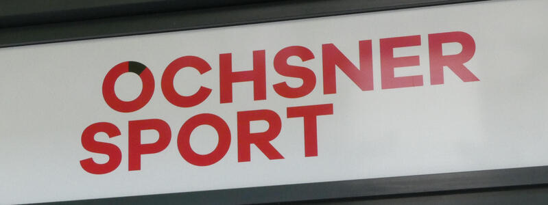 Sign OCHSNER SPORT in red. The O has a black arc of about 20 degrees near the top.