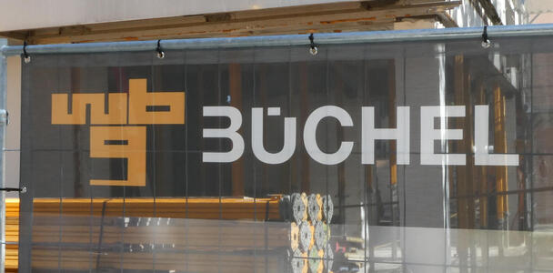 Logo for BÜCHEL. The B is missing the vertical bar, and the Ü has only one square dot in imiddle with the right upper part of the U cut off to below the umlaut.