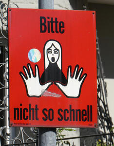 Drawing of woman holding out hands in “stop” gesture. Black text on red background: Bitte nicht so schnell
