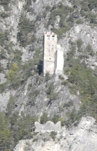 Stone tower standing alone on the side of a mountain.