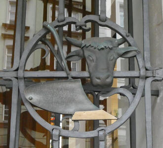 Metalwork with head of an ox and a plow. The plow has a gold-coloured plowshare.
