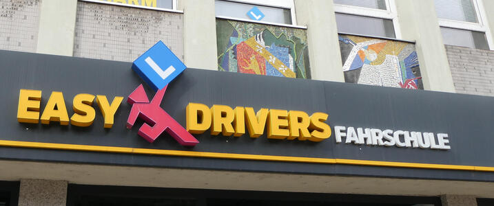 Logo for Easy Drivers Driving School. Has a tangram-shaped man holding the letter L (for learner) at an angle
