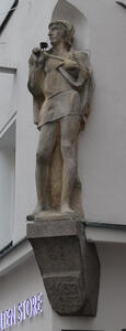 Stone sculpture of man in medieval clothing, holding a flower.