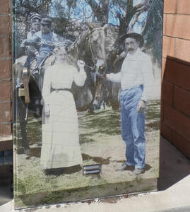 Man and woman in 1900s western clothing; man holding a horse with two children in the saddle