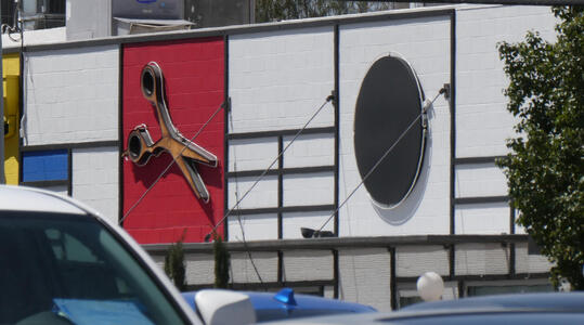 Building with mondrian-like pattern on wall and giant pair of scissors