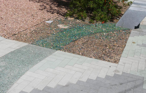 Green stripe on concrete turns to a channel of green glass crystals in off-sidewalk area