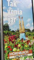 Person standing on head with head obscured by flowers in garden. Text: “That’s how the garden smells. You can do it with us.”