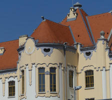 Building with yellow facade, curved bay-window style exterior, and sundial